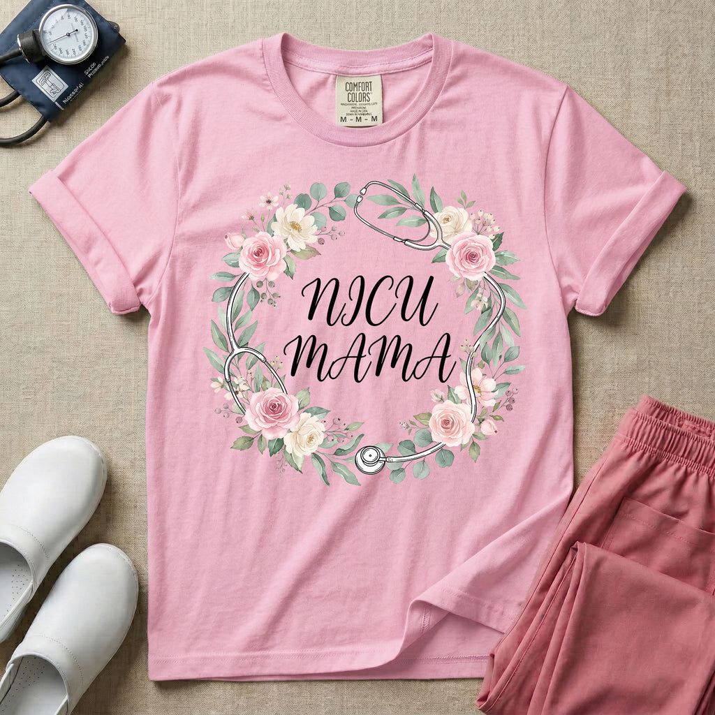 A t-shirt featuring a boho floral wreath composed of pink and cream roses intertwined with a stethoscope, surrounding the text NICU MAMA in elegant typography.