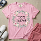 A t-shirt featuring a boho floral wreath composed of pink and cream roses intertwined with a stethoscope, surrounding the text NICU MAMA in elegant typography.