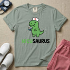 A cute t-shirt for NICU nurses featuring a cartoon green dinosaur wearing a nurse hat with a red cross and holding a blue pacifier above the funny text NICUSAURUS.