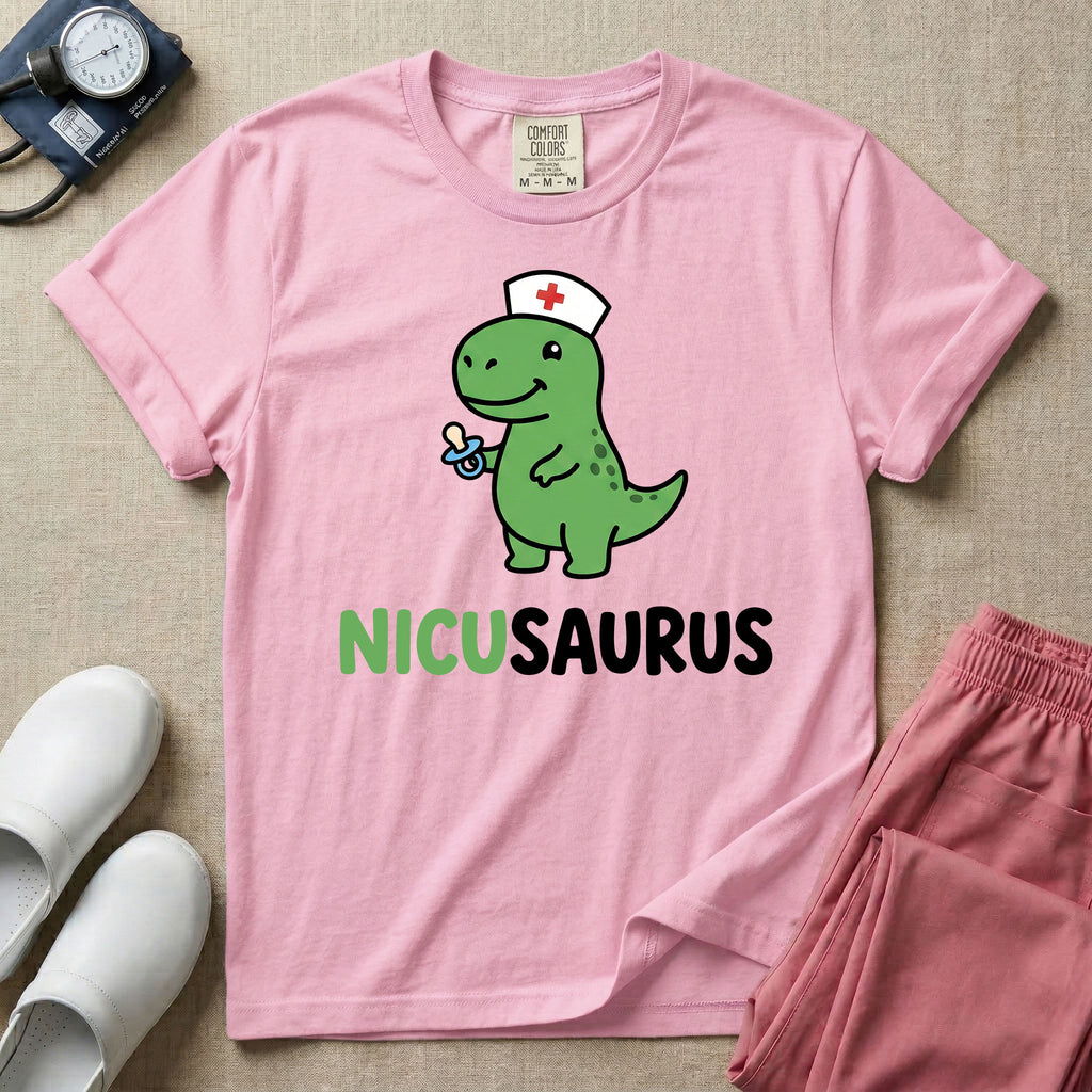 A cute t-shirt for NICU nurses featuring a cartoon green dinosaur wearing a nurse hat with a red cross and holding a blue pacifier above the funny text NICUSAURUS.