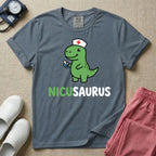 A cute t-shirt for NICU nurses featuring a cartoon green dinosaur wearing a nurse hat with a red cross and holding a blue pacifier above the funny text NICUSAURUS.