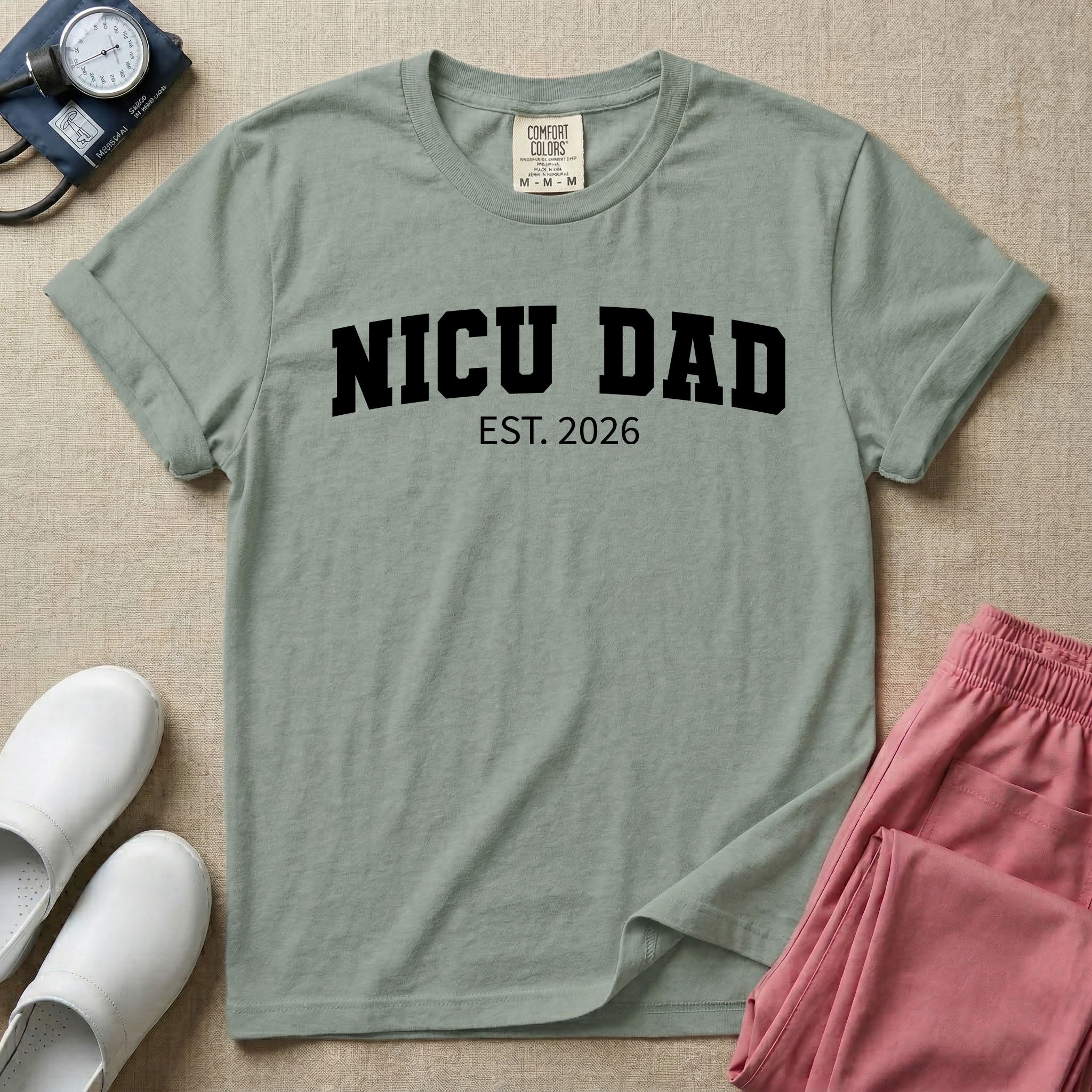 A minimalist personalized t-shirt for the NICU unit featuring bold white collegiate varsity lettering that reads NICU DAD arched over the text EST. 2026.