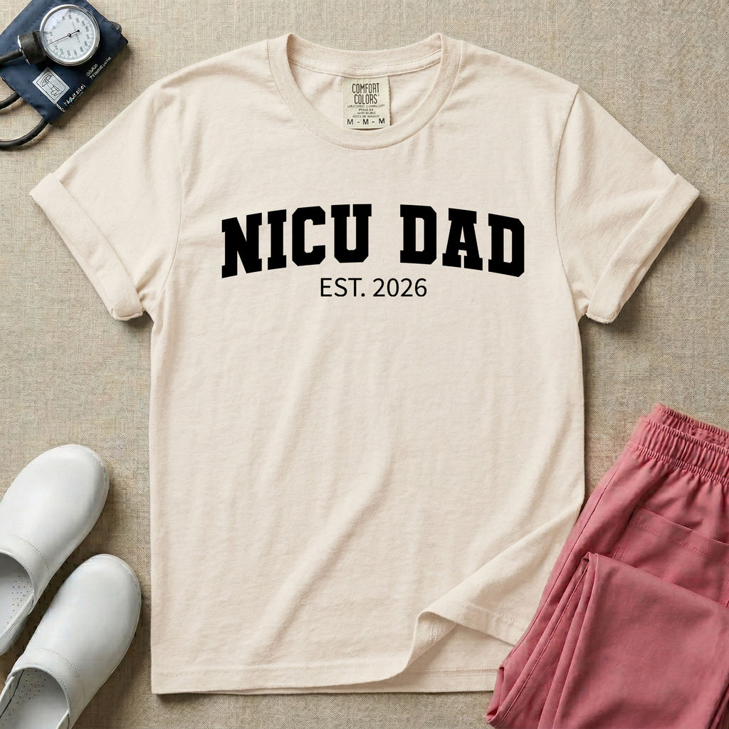 A minimalist personalized t-shirt for the NICU unit featuring bold white collegiate varsity lettering that reads NICU DAD arched over the text EST. 2026.