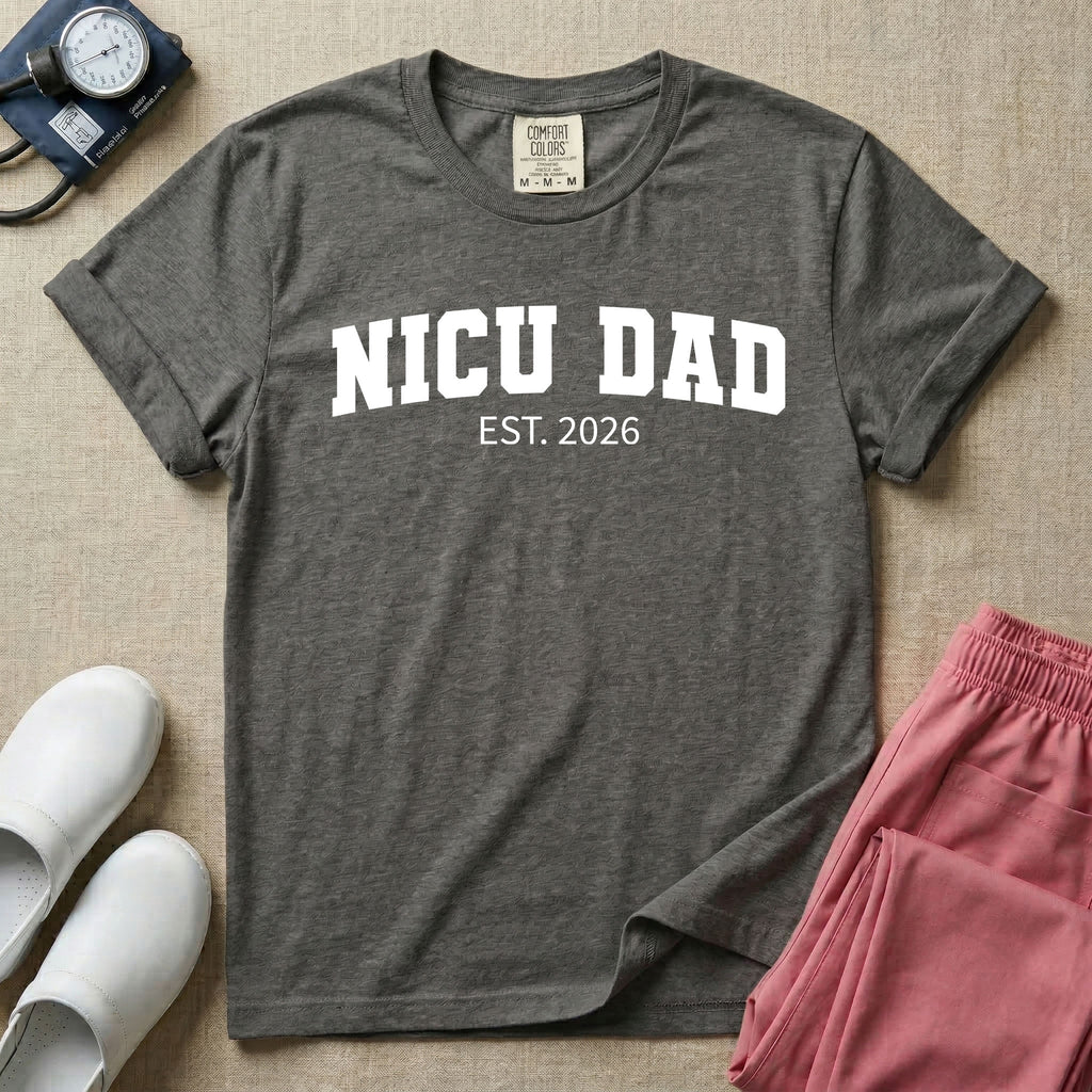 A minimalist personalized t-shirt for the NICU unit featuring bold white collegiate varsity lettering that reads NICU DAD arched over the text EST. 2026.
