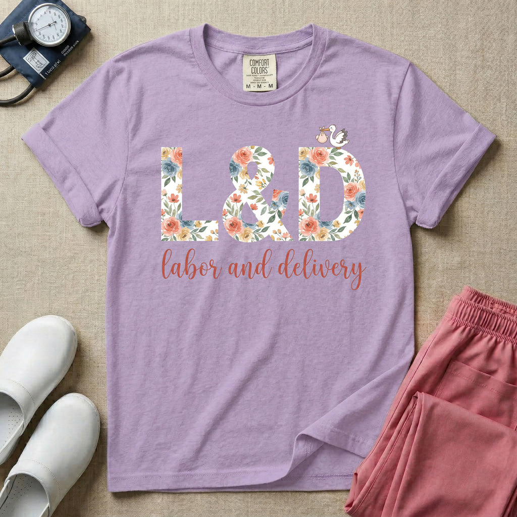 A Labor and Delivery nurse design featuring the large letters L&D filled with a gorgeous boho floral pattern of peach and blue flowers, with a tiny cartoon stork resting on top of the letter D, all positioned above the elegant white script text labor and delivery.