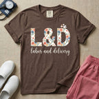 A Labor and Delivery nurse design featuring the large letters L&D filled with a gorgeous boho floral pattern of peach and blue flowers, with a tiny cartoon stork resting on top of the letter D, all positioned above the elegant white script text labor and delivery.