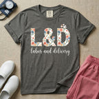 A Labor and Delivery nurse design featuring the large letters L&D filled with a gorgeous boho floral pattern of peach and blue flowers, with a tiny cartoon stork resting on top of the letter D, all positioned above the elegant white script text labor and delivery.