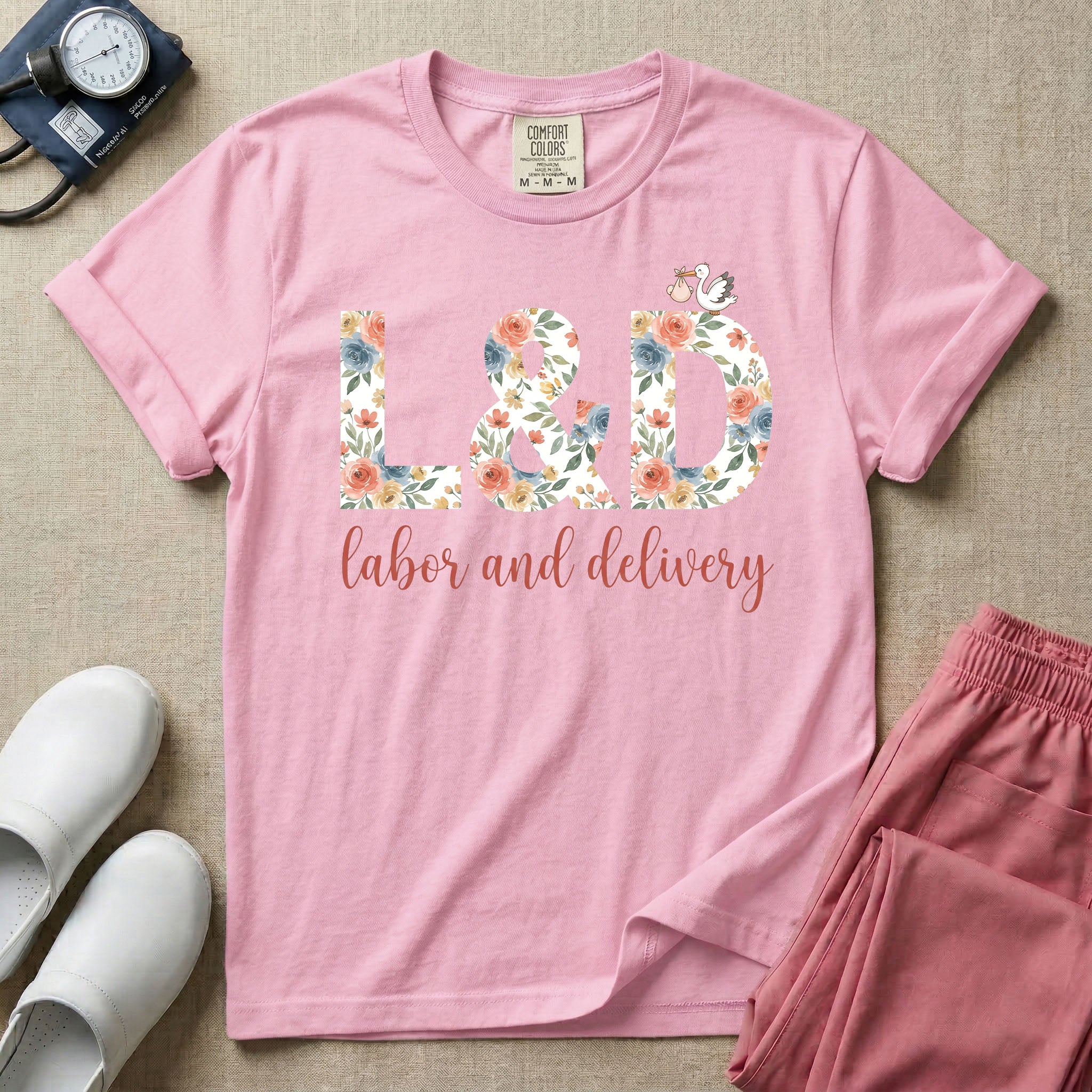 A Labor and Delivery nurse design featuring the large letters L&D filled with a gorgeous boho floral pattern of peach and blue flowers, with a tiny cartoon stork resting on top of the letter D, all positioned above the elegant white script text labor and delivery.