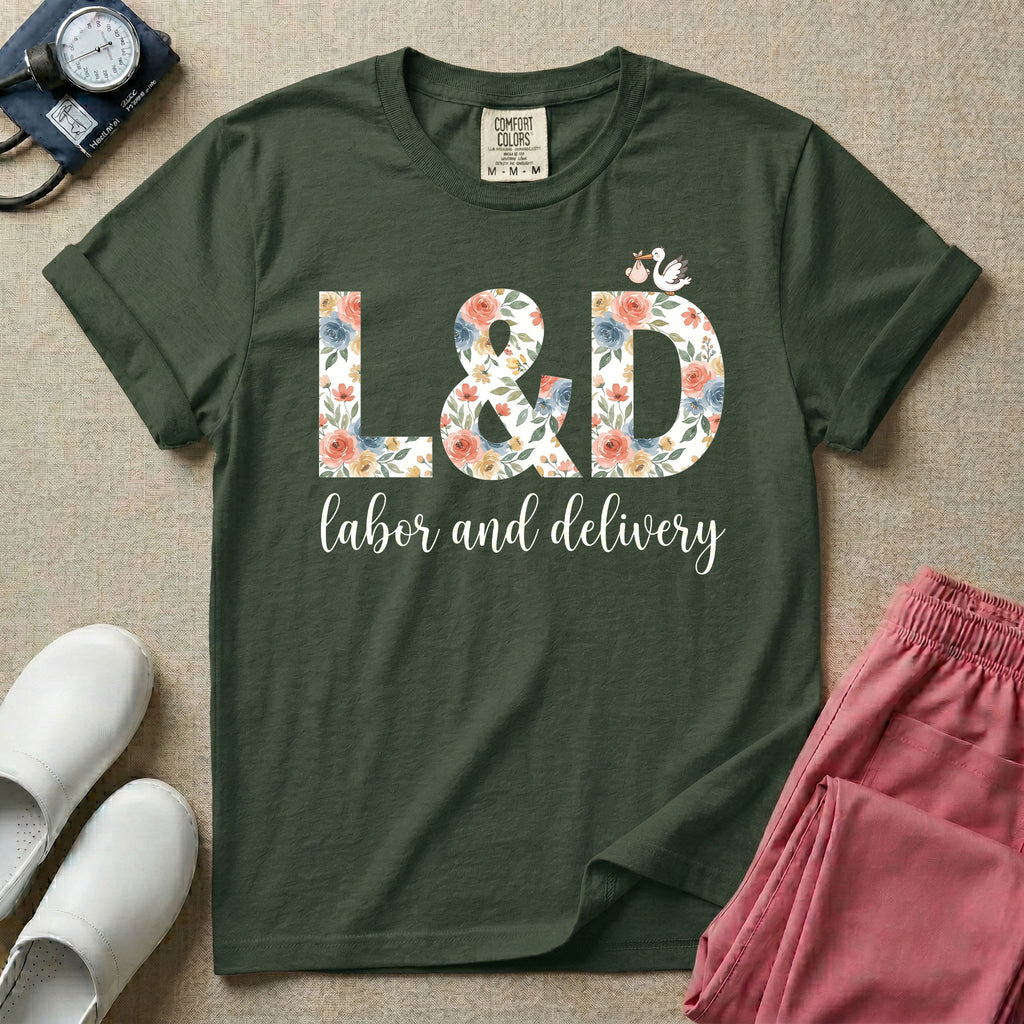A Labor and Delivery nurse design featuring the large letters L&D filled with a gorgeous boho floral pattern of peach and blue flowers, with a tiny cartoon stork resting on top of the letter D, all positioned above the elegant white script text labor and delivery.