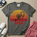 Retro vintage graphic featuring a distressed sunset background with a heart-shaped stethoscope enclosing tiny baby footprints above the bold text NICU.