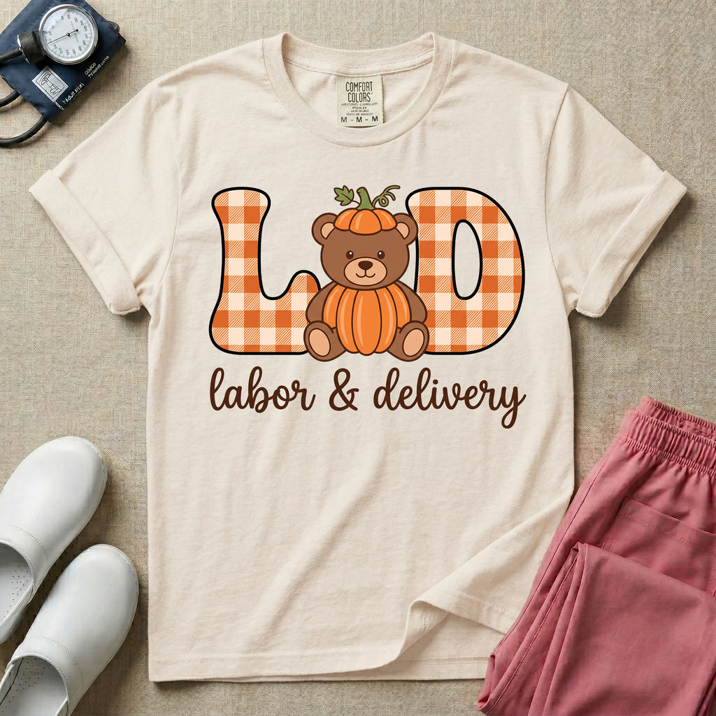 Labor and Delivery nurse autumn design featuring large gingham patterned letters spelling L&D centered with a cute teddy bear wearing a pumpkin costume and hat above cursive text reading labor and delivery.