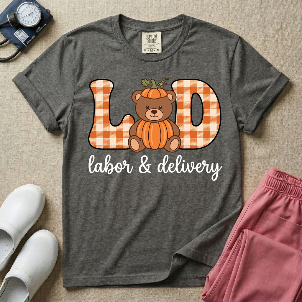 Labor and Delivery nurse autumn design featuring large gingham patterned letters spelling L&D centered with a cute teddy bear wearing a pumpkin costume and hat above cursive text reading labor and delivery.
