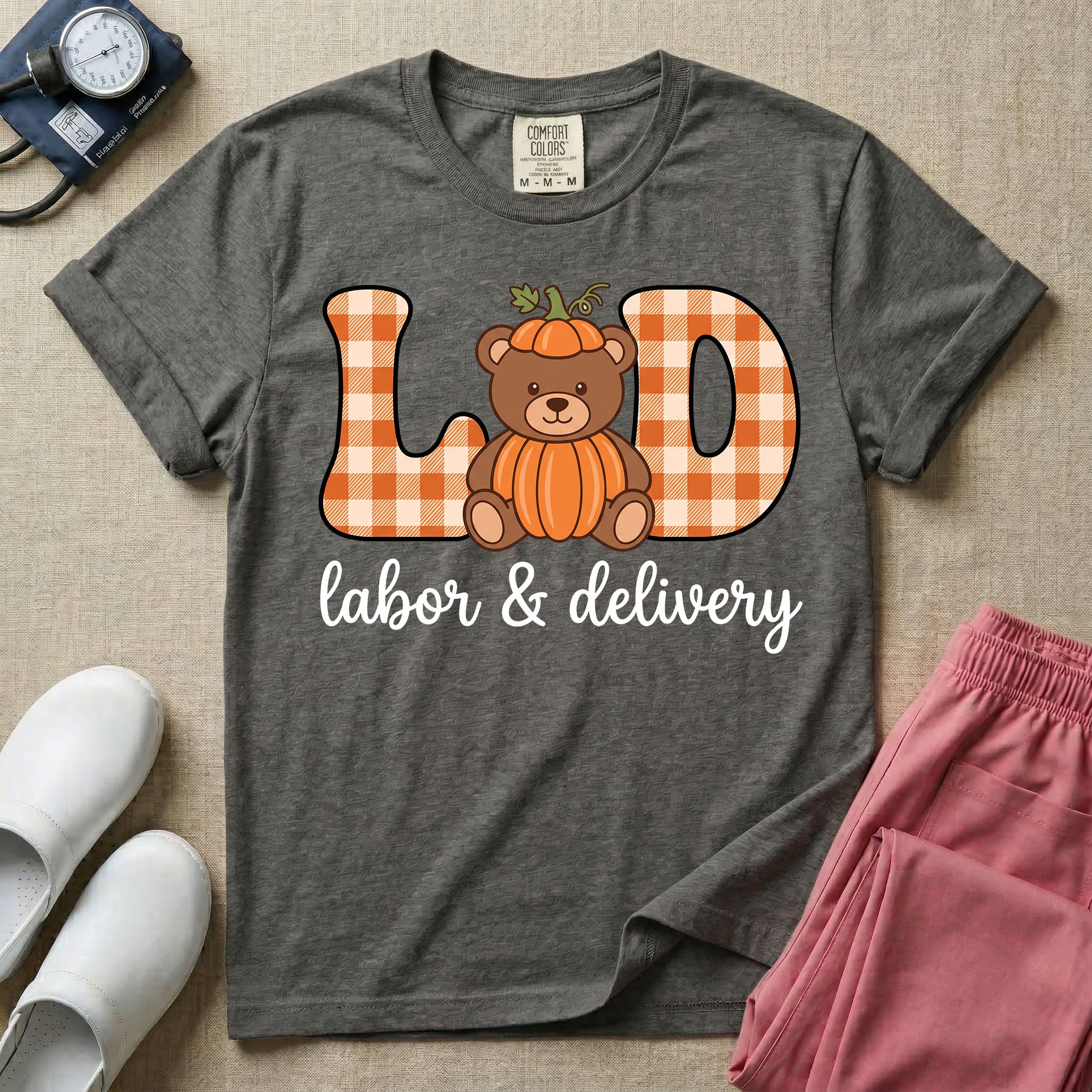 Labor and Delivery nurse autumn design featuring large gingham patterned letters spelling L&D centered with a cute teddy bear wearing a pumpkin costume and hat above cursive text reading labor and delivery.