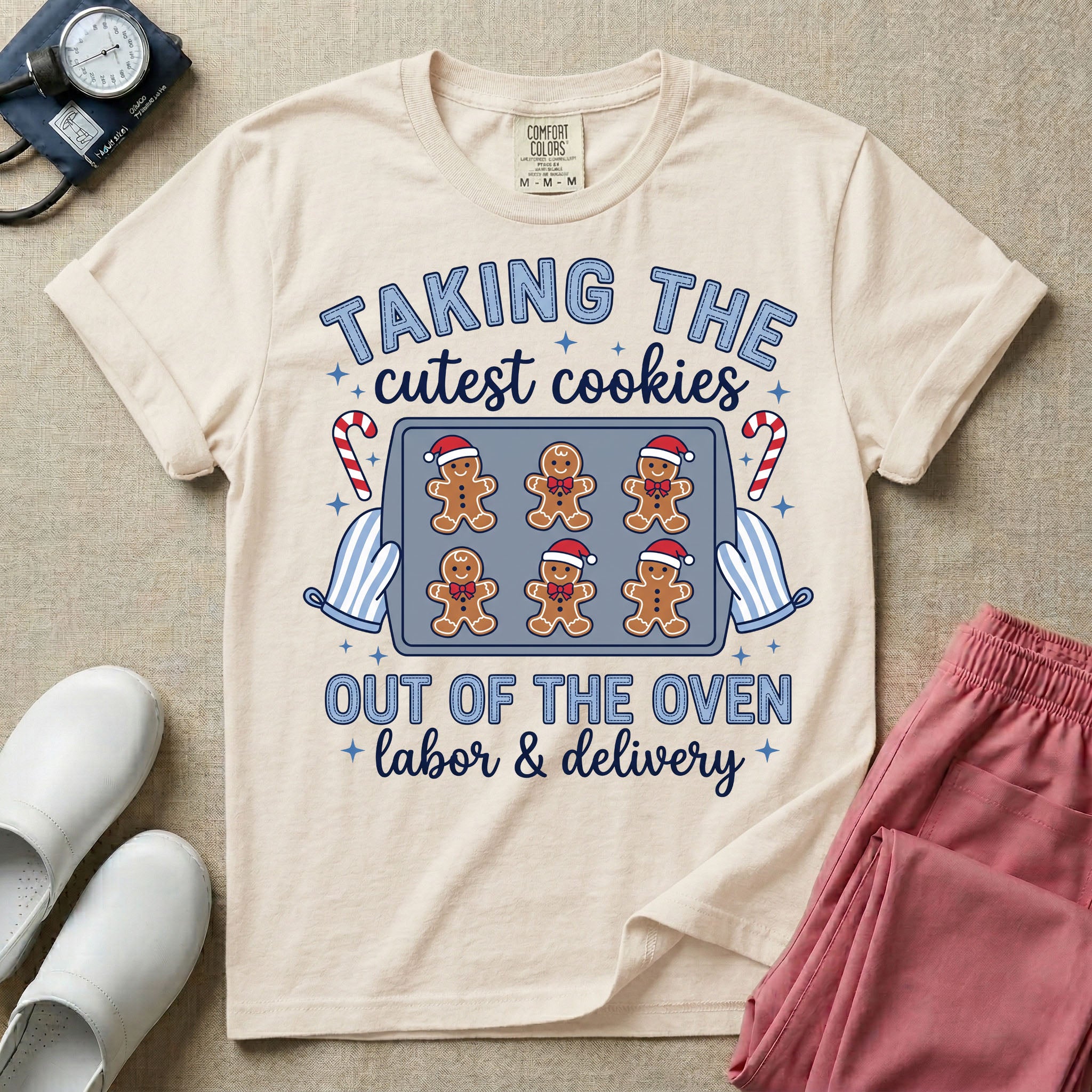 Christmas Labor and Delivery nurse design featuring the text Taking The Cutest Cookies Out Of The Oven surrounded by a baking sheet of gingerbread baby cookies in Santa hats, oven mitts, candy canes, and script text reading labor and delivery.