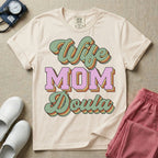 Retro birth worker design featuring stacked layered 3D lettering spelling Wife Mom Doula with vintage cursive script and collegiate block typography.