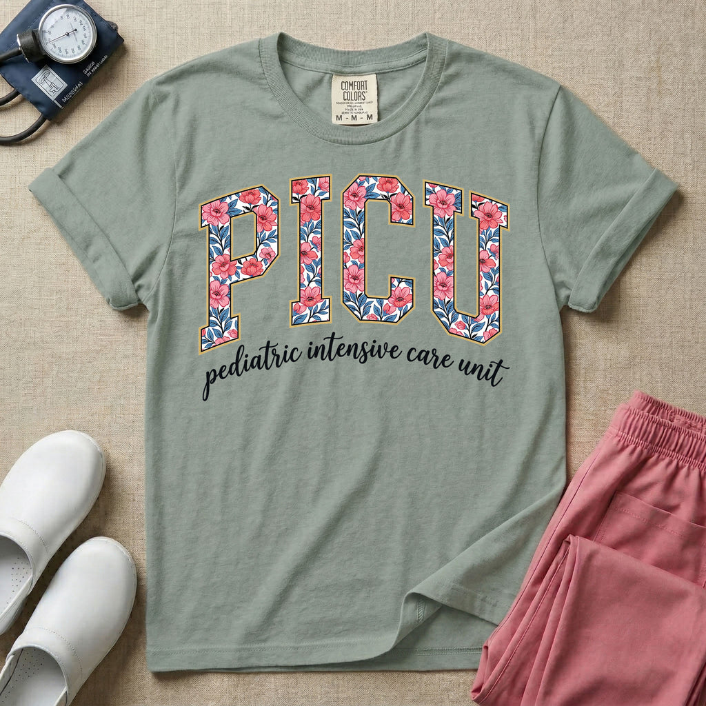 A boho pediatric intensive care nursing t-shirt featuring the large block text "PICU" filled with a decorative floral pattern, positioned above the cursive white text "pediatric intensive care unit".