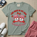 A t-shirt featuring two jars of strawberry jam surrounded by small hearts and strawberries with the text THE NICU IS MY JAM arched above and Neonatal ICU Nurse written in a retro script below.