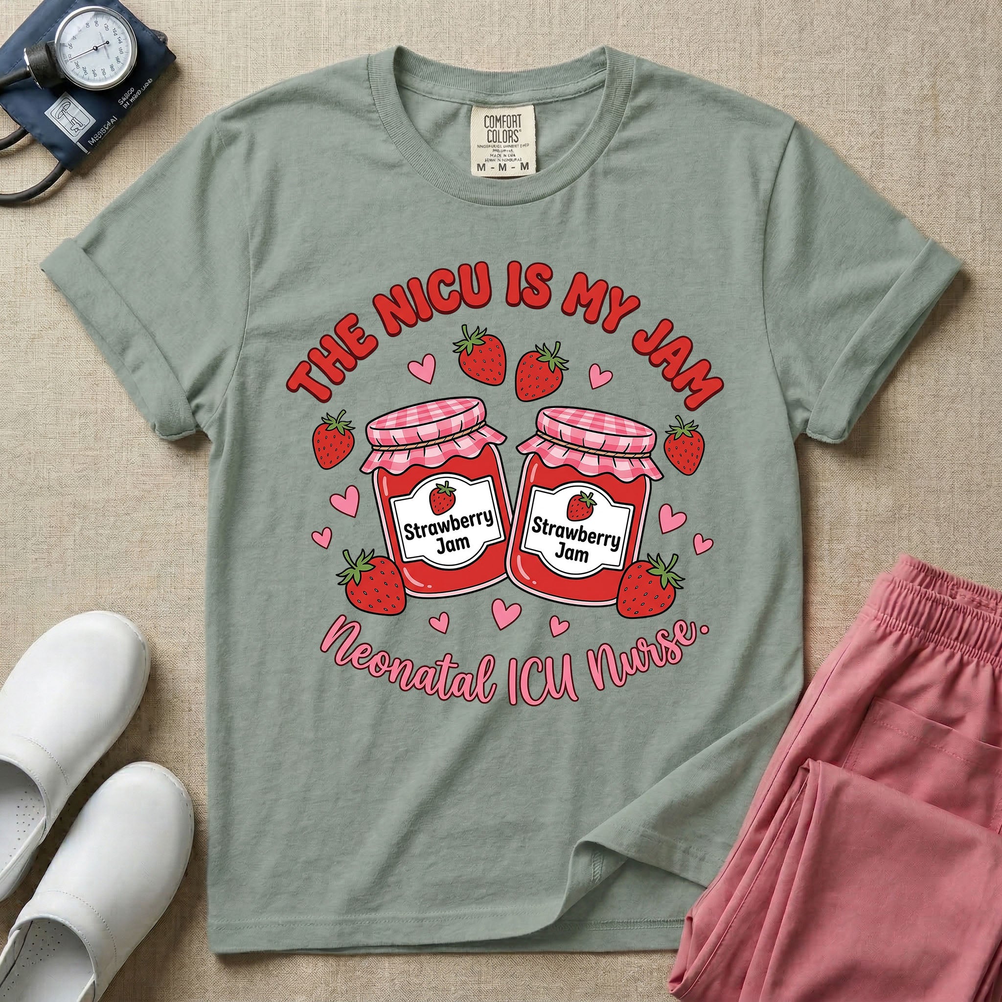 A t-shirt featuring two jars of strawberry jam surrounded by small hearts and strawberries with the text THE NICU IS MY JAM arched above and Neonatal ICU Nurse written in a retro script below.