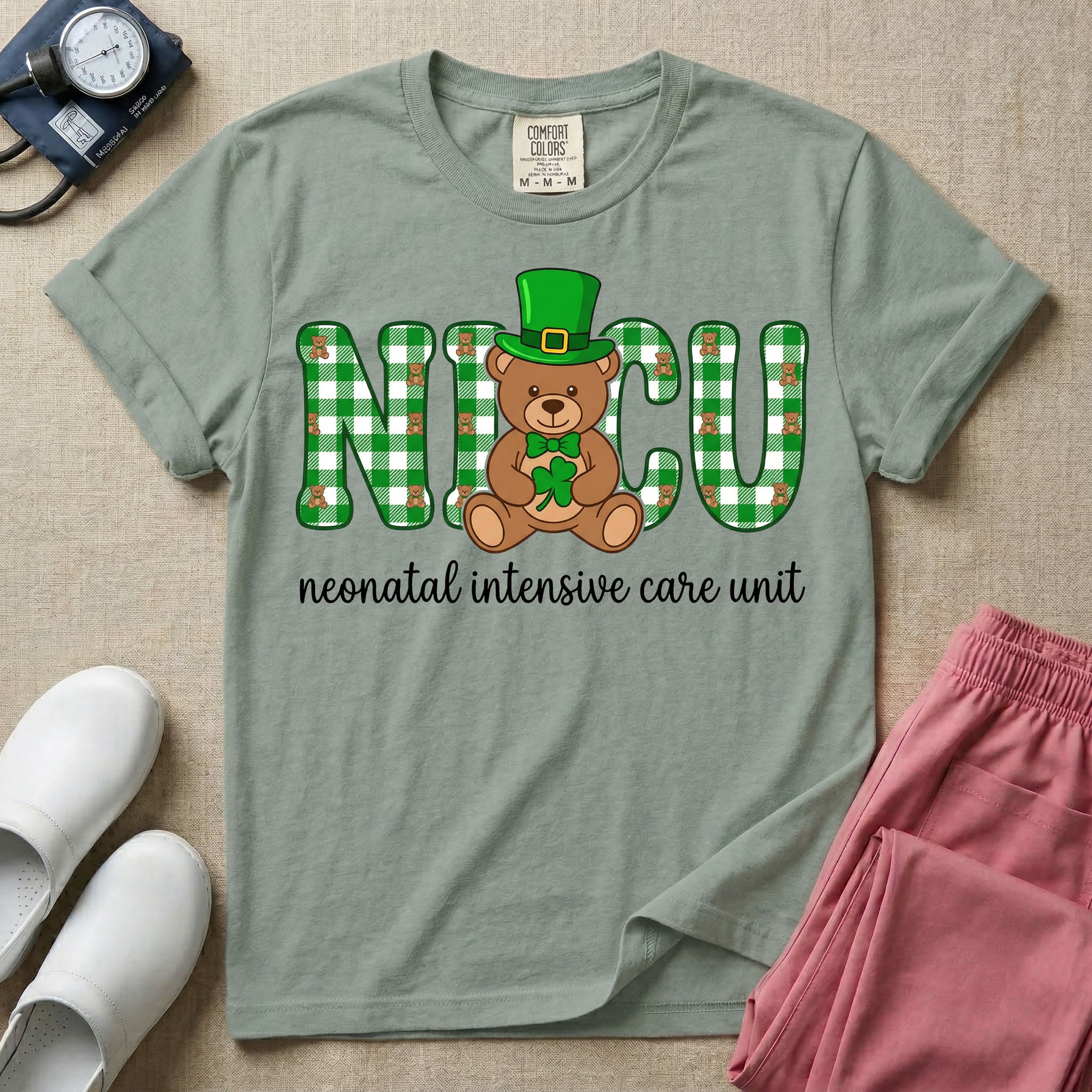 A graphic for a Neonatal Intensive Care Unit featuring the word 'NICU' in green and white plaid patterned letters, with a cute brown teddy bear wearing a leprechaun hat and holding a shamrock sitting in the middle, and the cursive text 'neonatal intensive care unit' underneath.