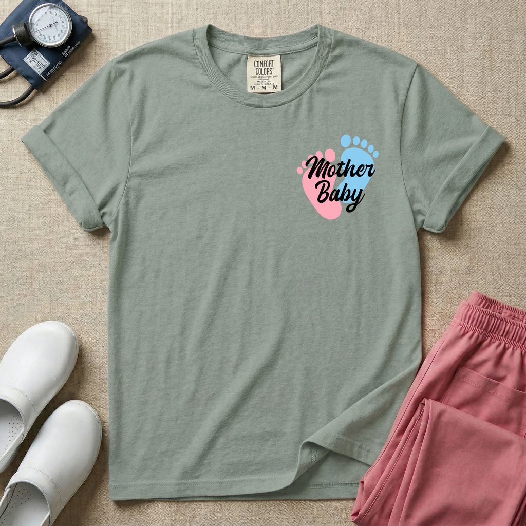 A minimalist postpartum nursing t-shirt featuring a small left chest graphic of two baby footprints, one pink and one blue, with the cursive white text "Mother Baby" written across them.
