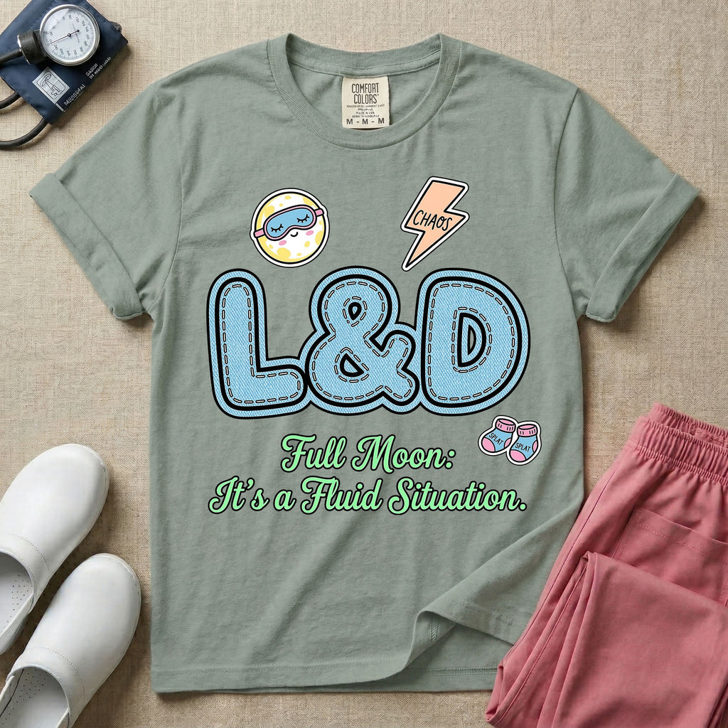 A humorous Labor and Delivery nurse graphic featuring large, light blue varsity-style letters spelling L&D with a pink dashed outline, surrounded by small patch-like icons of a baby and a lightning bolt, sitting above cursive text that reads Full Moon: It's a Fluid Situation.