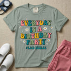 A retro graphic tee for labor and delivery nurses featuring bubble lettering that reads "EVERYDAY IS A BIRTHDAY PARTY #L&D NURSE" surrounded by small daisies and stars.