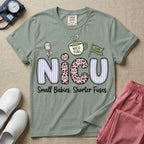 A funny t-shirt for NICU nurses featuring the large text "NICU" patterned with purple stripes and pink leopard print containing grumpy cat faces, accompanied by graphics of an IV bag with a pink bow, a steaming coffee cup reading "NICU FUEL", a green flag saying "Code Grumpy", and the bottom text "Small Babies. Shorter Fuses."