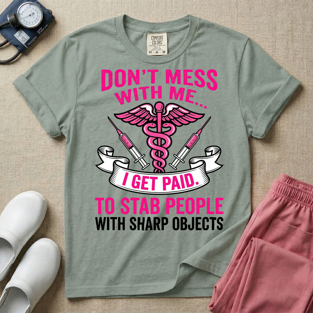 General nursing and ER t-shirt featuring a pink and black caduceus medical symbol flanked by two syringes alongside the humorous text "DON'T MESS WITH ME... I GET PAID TO STAB PEOPLE WITH SHARP OBJECTS".