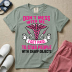 General nursing and ER t-shirt featuring a pink and black caduceus medical symbol flanked by two syringes alongside the humorous text "DON'T MESS WITH ME... I GET PAID TO STAB PEOPLE WITH SHARP OBJECTS".
