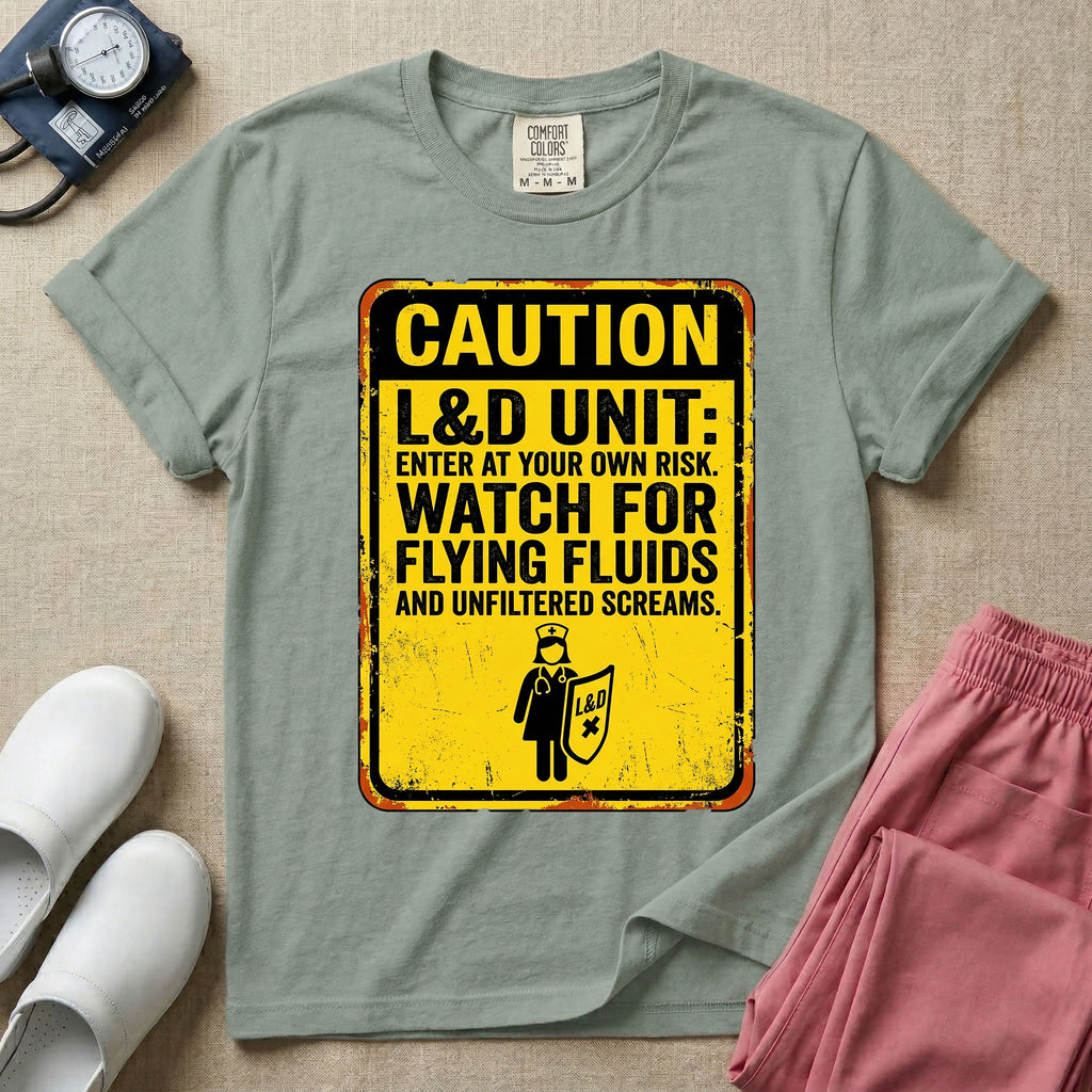 A humorous graphic tee for labor and delivery nurses featuring a distressed caution sign design with the text "CAUTION L&D UNIT: ENTER AT YOUR OWN RISK. WATCH FOR FLYING FLUIDS AND UNFILTERED SCREAMS." above a stick figure nurse holding a shield.