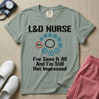 A humorous Labor and Delivery nurse t-shirt featuring a cervical dilation chart graphic highlighting 10cm, with the text "L&D NURSE" at the top and "I've Seen It All And I'm Still Not Impressed" at the bottom.