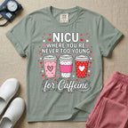 A Valentine's Day themed graphic for a Neonatal Intensive Care Unit featuring the text 'NICU WHERE YOU'RE NEVER TOO YOUNG' stacked above three to-go coffee cups decorated with heart patterns, with 'for Caffeine' written in script at the bottom, all surrounded by small red and pink hearts.
