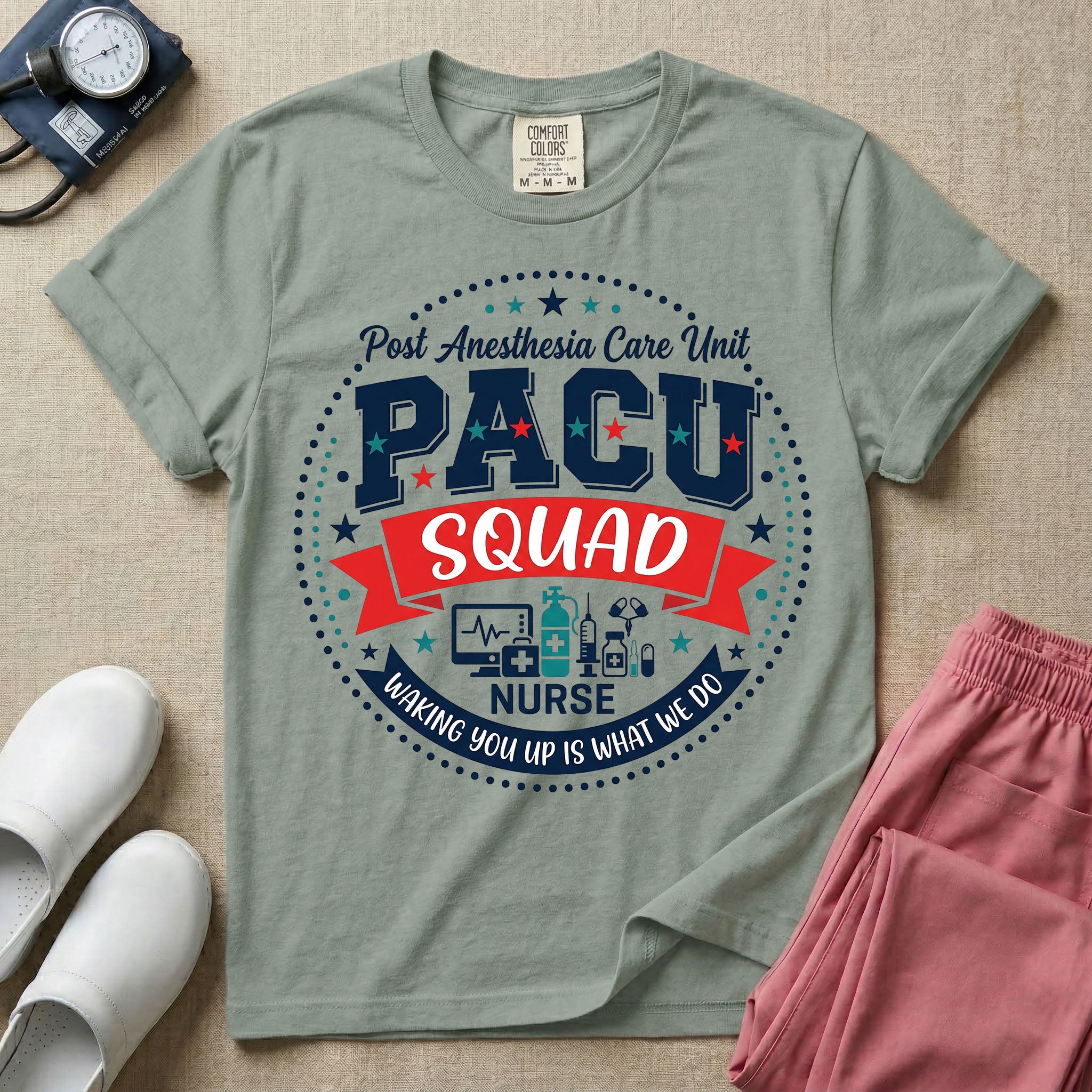A t-shirt featuring a circular badge design with the text PACU SQUAD in block letters, medical icons like a heart monitor and stethoscope, and the phrase Waking You Up Is What We Do.