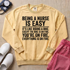 Funny Being A Nurse Is Easy Bike On Fire Sarcastic Nurse Sweatshirt - Butter Comfort Colors Sweatshirt | HugTee