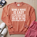 Funny Being A Nurse Is Easy Bike On Fire Sarcastic Nurse Sweatshirt - Terracotta Comfort Colors Sweatshirt | HugTee