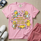 General nursing t-shirt featuring a chaotic group of cartoon ducklings dressed as medical professionals with the text "MOST DEFINITELY NOT ALL IN A ROW" on a sage green garment, in blossom color.