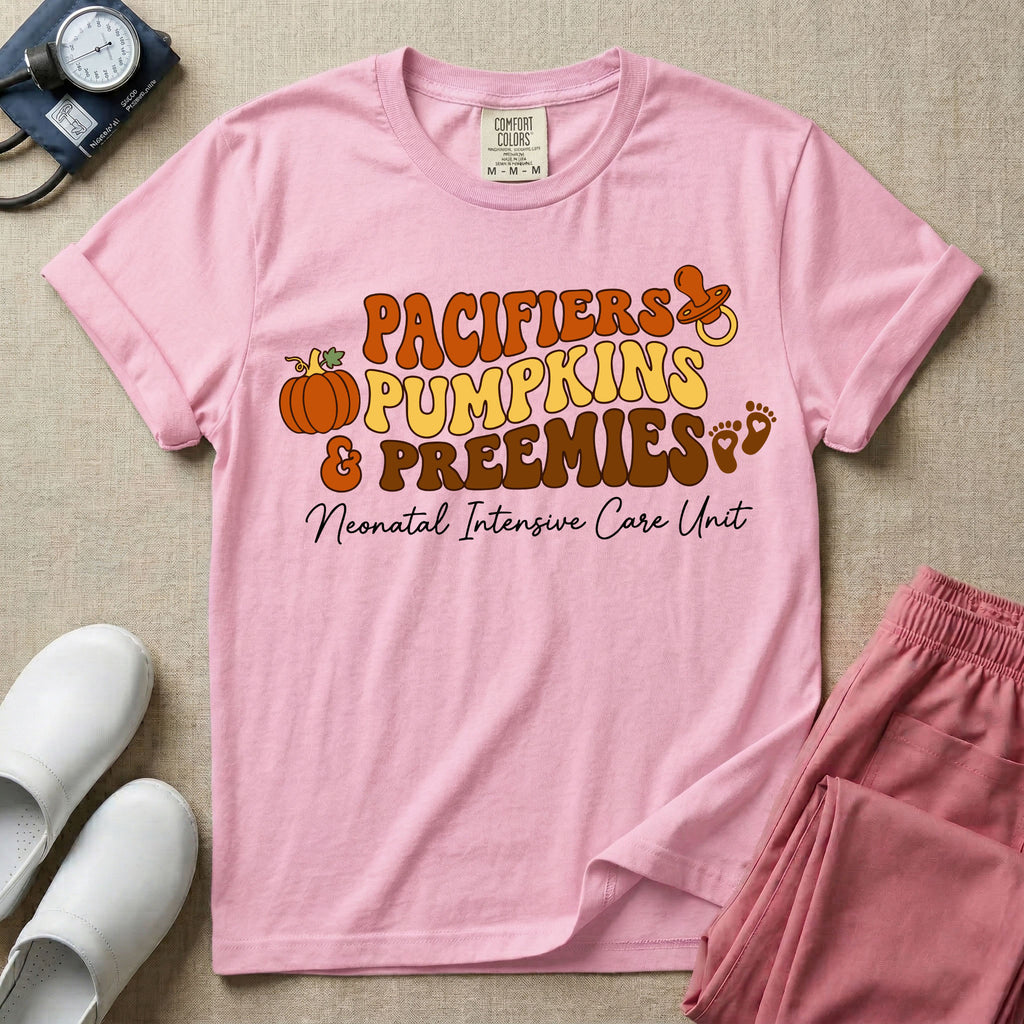 A t-shirt featuring the stacked text PACIFIERS PUMPKINS & PREEMIES in wavy orange, yellow, and brown retro lettering decorated with a pumpkin, pacifier, and baby footprints, with Neonatal Intensive Care Unit written in cursive below.