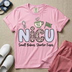 A funny t-shirt for NICU nurses featuring the large text "NICU" patterned with purple stripes and pink leopard print containing grumpy cat faces, accompanied by graphics of an IV bag with a pink bow, a steaming coffee cup reading "NICU FUEL", a green flag saying "Code Grumpy", and the bottom text "Small Babies. Shorter Fuses."