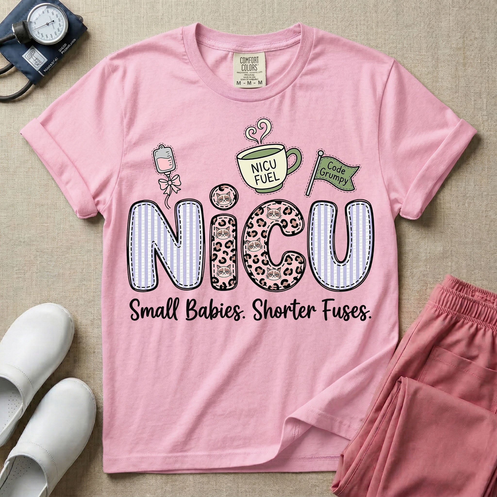 A funny t-shirt for NICU nurses featuring the large text "NICU" patterned with purple stripes and pink leopard print containing grumpy cat faces, accompanied by graphics of an IV bag with a pink bow, a steaming coffee cup reading "NICU FUEL", a green flag saying "Code Grumpy", and the bottom text "Small Babies. Shorter Fuses."