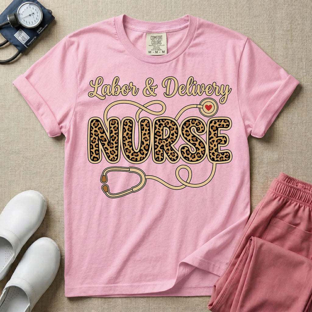A graphic t-shirt for a Labor and Delivery unit featuring the text 'Labor & Delivery' in beige script above the word 'NURSE' in large leopard print letters, intertwined with an illustration of a stethoscope that features a small red heart on the chest piece.