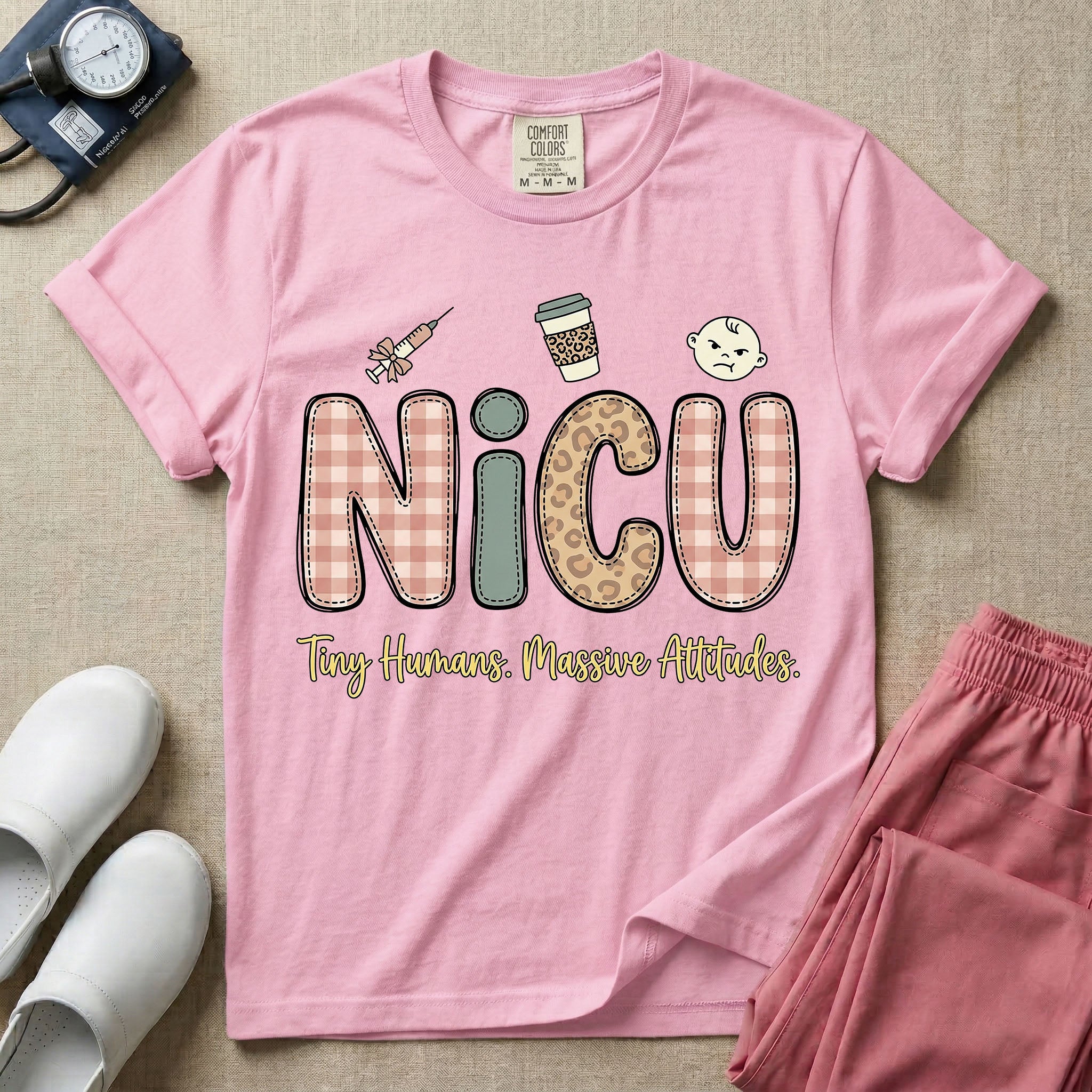 A humorous t-shirt for NICU nurses featuring the large text "NICU" in plaid and patterned letters with the phrase "Tiny Humans. Massive Attitudes." underneath, accompanied by small cute graphics of a syringe, an iced coffee cup, and a baby's face.