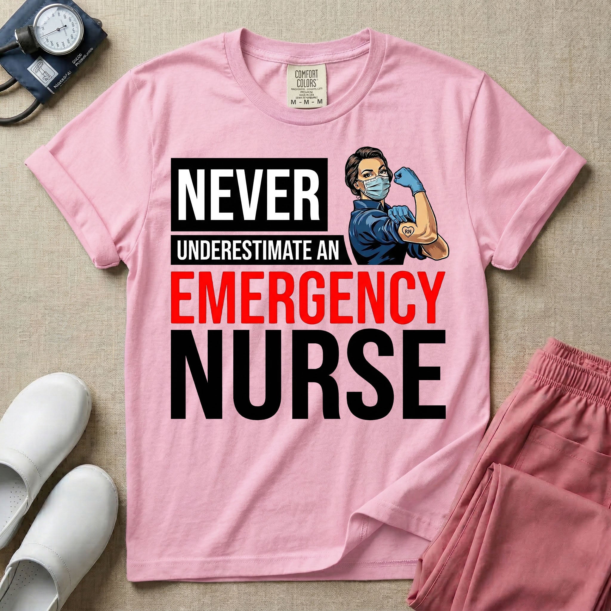 A retro ER nursing t-shirt featuring the bold text "NEVER UNDERESTIMATE AN EMERGENCY NURSE" alongside a vintage graphic of a masked nurse flexing her arm in a classic Rosie the Riveter pose