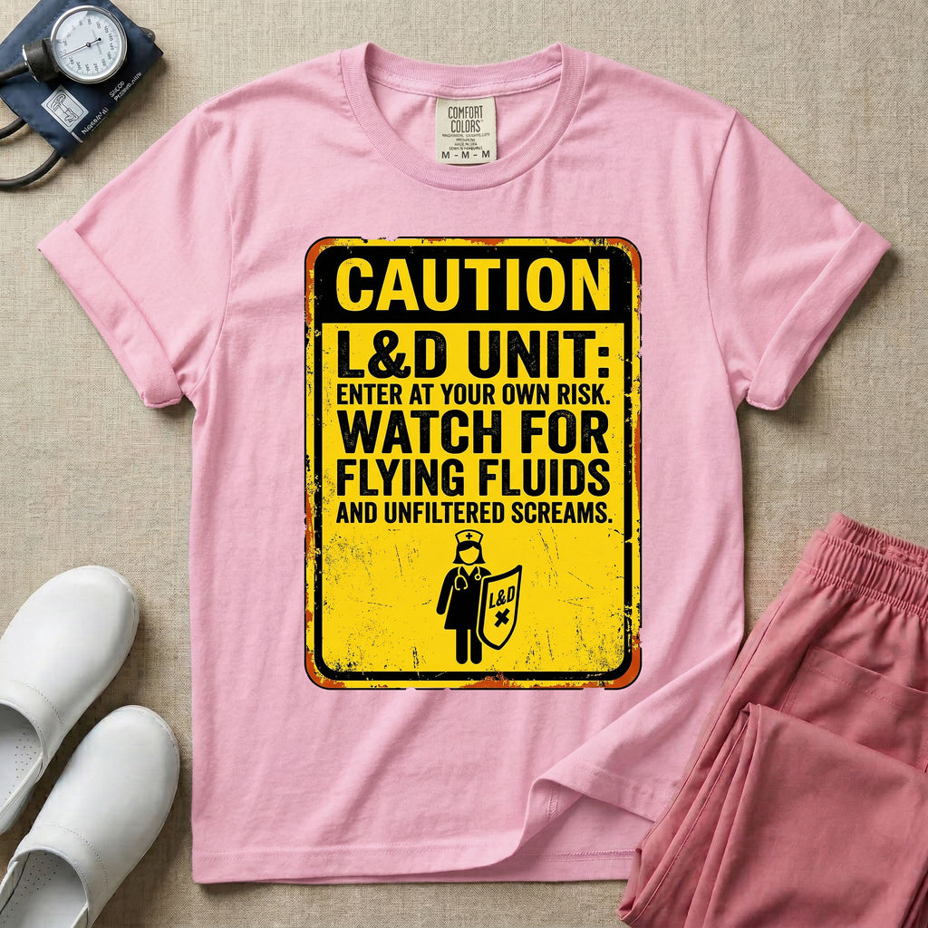 A humorous graphic tee for labor and delivery nurses featuring a distressed caution sign design with the text "CAUTION L&D UNIT: ENTER AT YOUR OWN RISK. WATCH FOR FLYING FLUIDS AND UNFILTERED SCREAMS." above a stick figure nurse holding a shield.