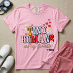 A t-shirt featuring the text Tiny Humans are my favorite in colorful retro bubble letters decorated with daisies, sparkles, and red hearts with a small NICU heart logo at the bottom.