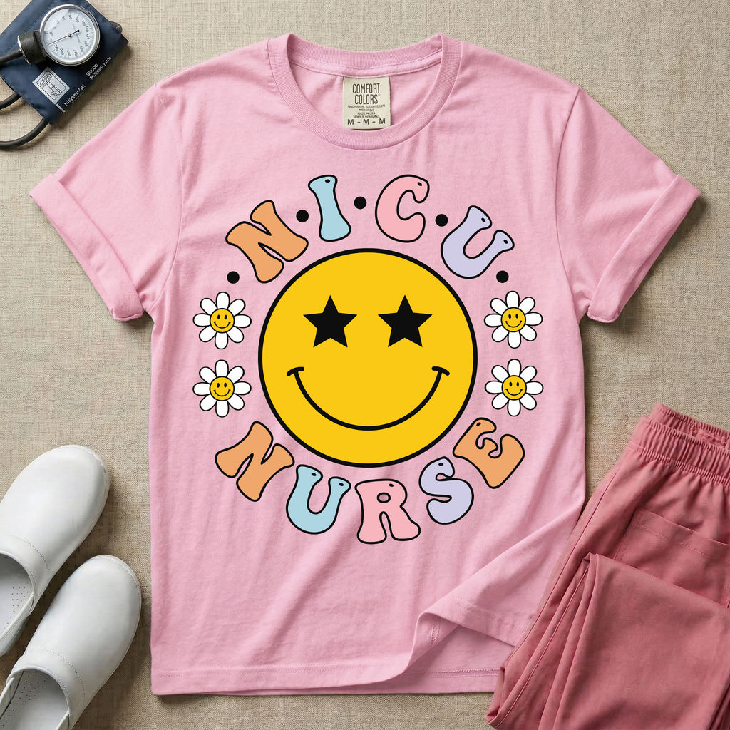 A t-shirt featuring a large yellow smiley face with star eyes surrounded by smiley face daisies and the text N.I.C.U. NURSE in pastel retro bubble lettering.