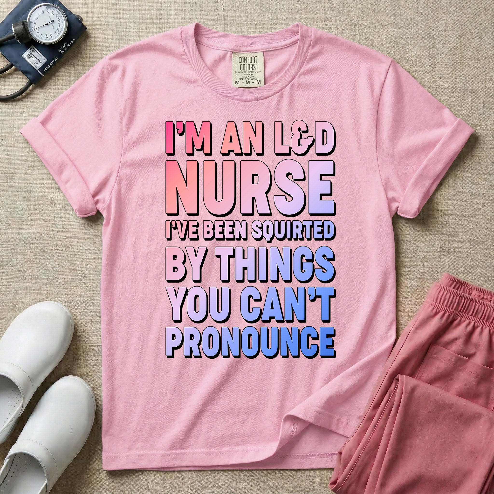 A humorous graphic tee for labor and delivery nurses featuring bold, gradient block lettering that reads "I'M AN L&D NURSE I'VE BEEN SQUIRTED BY THINGS YOU CAN'T PRONOUNCE".