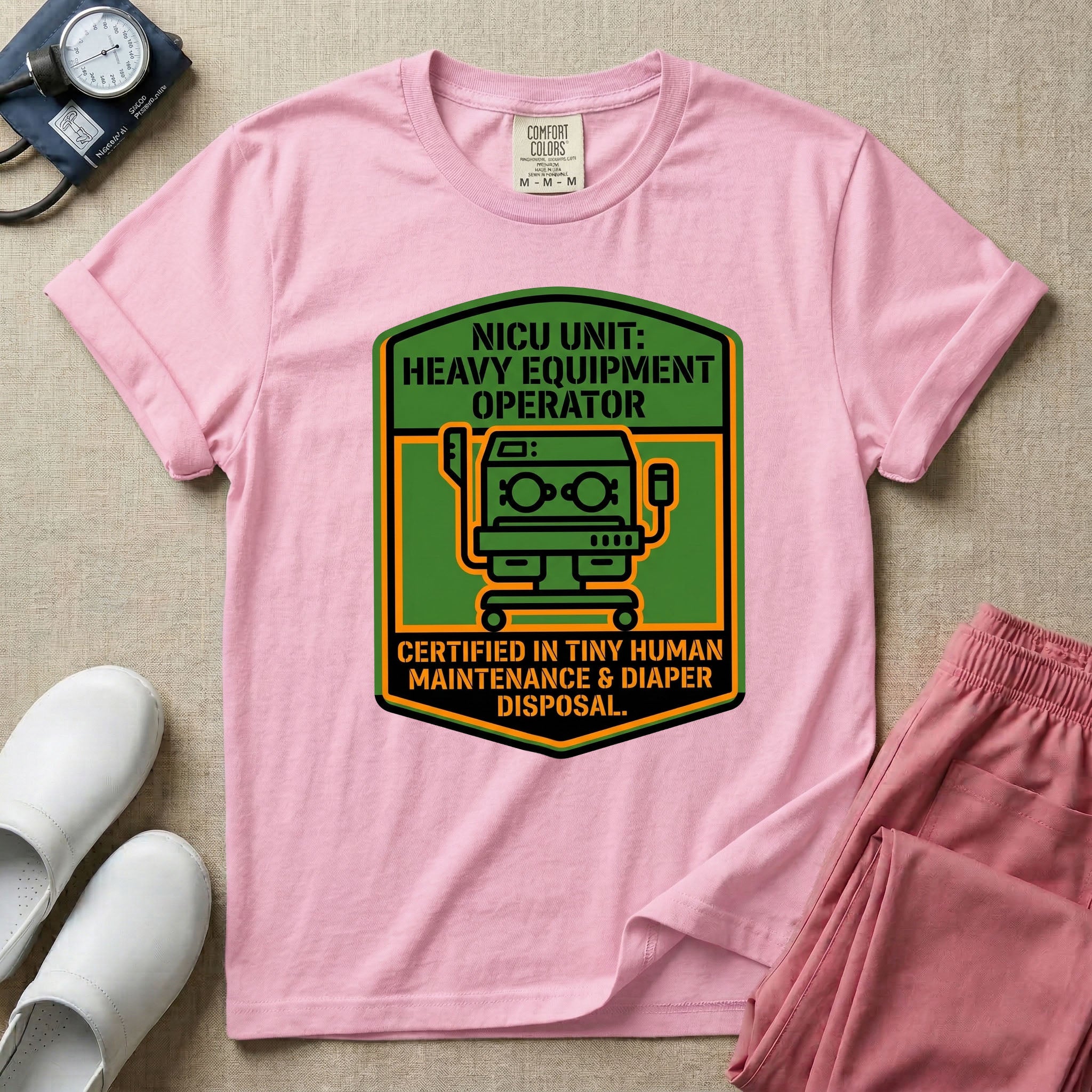 A graphic resembling a patch with green borders and orange inner sections featuring an illustration of a medical incubator in the center, with the text 'NICU UNIT: HEAVY EQUIPMENT OPERATOR' at the top and 'CERTIFIED IN TINY HUMAN MAINTENANCE & DIAPER DISPOSAL' at the bottom.
