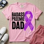 A graphic for the Neonatal Intensive Care Unit featuring the stacked, bold white text 'BADASS PREEMIE DAD' next to a large, textured purple awareness ribbon.