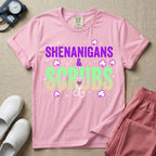 General nursing St. Patrick's Day t-shirt featuring a retro wavy font with the text "SHENANIGANS & SCRUBS" surrounded by shamrock graphics and a stethoscope.