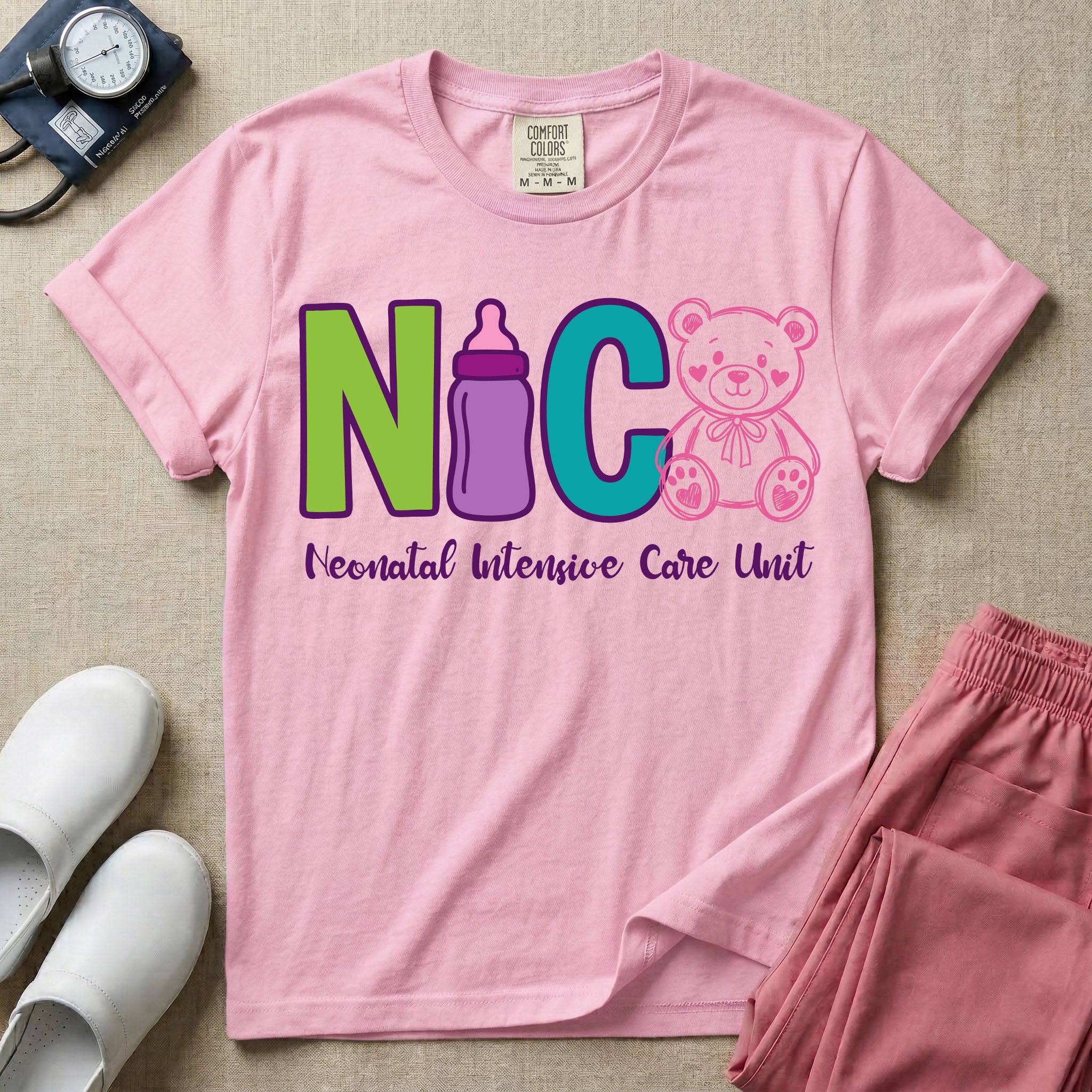 A t-shirt featuring the acronym NICU creatively spelled out using a green letter N, a purple baby bottle, a teal letter C, and a pink outlined teddy bear, with the words Neonatal Intensive Care Unit written in cursive script below.